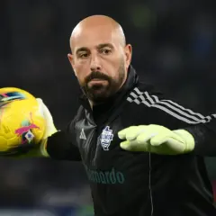 Reina, hiszpański bramkarz, w rękawicach łapie żółtą piłkę.