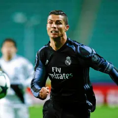 Cristiano Ronaldo w czarnej koszulce Realu Madryt biegnie z piłką.