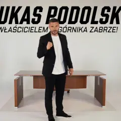 Łukasz Podolski, właściciel Górnika Zabrze, w garniturze przed biurkiem. Najnowsze wiadomości z klubu.