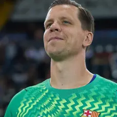 Wojciech Szczęsny w zielonej bramkarskiej koszulce, z uśmiechem na twarzy, gotowy do gry.