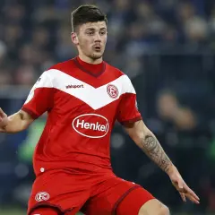Jeden z zawodników Hertha BSC w czerwonej koszulce z białymi elementami i logo "Henkel" na piersi, z tatuażem kompasu na ramieniu.