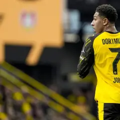 Piłkarz Jobe Bellingham w żółtej koszulce z numerem 7 i napisem "DORTMUND" na plecach, na tle trybun.