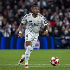 David Alaba w białej koszulce Realu Madryt z numerem 4 biegnie z piłką na murawie, skupiony na grze.