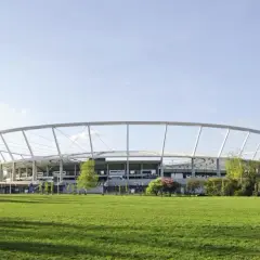 Nowoczesny Stadion Śląski otoczony zielenią, z charakterystyczną, okrągłą konstrukcją dachu.