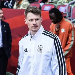Piłkarz reprezentacji Niemiec w białej kurtce z trzema paskami, gotowy do ważnych **niemcy mecze**.