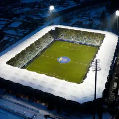 Zimowy wieczór na stadionie Gdynia Arka. Oświetlony stadion z zieloną murawą i śniegiem na trybunach, gotowy na mecz Bałtyk Gdynia.