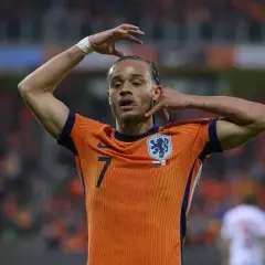 Piłkarz Xavi Simons w pomarańczowej koszulce reprezentacji Holandii z numerem 7, z rękami przy głowie.