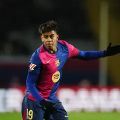 Młody zawodnik FC Barcelona w charakterystycznej koszulce, z numerem 19 na spodenkach, gestykuluje na boisku.