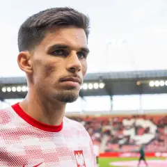 Filip Marchwiński w biało-czerwonej koszulce z godłem Polski, na tle stadionu.