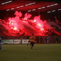 Chrobry Głogów stadion w ogniu rac! Kibice tworzą biało-czerwoną oprawę, a piłkarze grają na murawie.