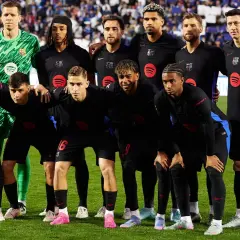 Drużyna FC Barcelona, znana z hiszpańskich zawodników, pozuje do zdjęcia w czarnych strojach.