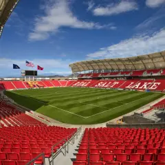 Puste trybuny stadionu Real Salt Lake, z zieloną murawą i niebieskim niebem.