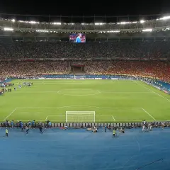 Piłkarze wychodzą na murawę stadionu olimpijskiego w Kijowie. Tłumy kibiców na trybunach, wielki ekran nad boiskiem.