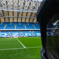 Pusta trybuna stadionu Lecha Poznań. Widoczne niebieskie sektory i miejsca, zielona murawa.