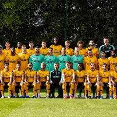 Wolverhampton Wanderers F.C. – zawodnicy w żółtych i zielonych strojach pozują do zdjęcia drużynowego na boisku.