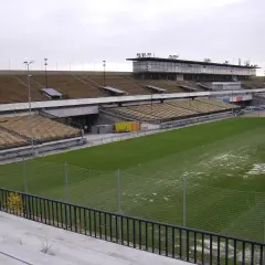 Pusta trybuna stadionu, największy stadion w Czechach, z zieloną murawą i ogrodzeniem.