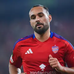 Piłkarz Ivi Lopez w czerwonej koszulce RKS Raków Częstochowa, z widocznym logo klubu i Adidasem. Mimo kontuzji, widać determinację na jego twarzy.
