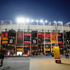 Nocny widok na **stadion z kontenerów Katar** z numerowanymi sekcjami i banerami Mistrzostw Świata FIFA 2022.