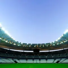 Puste trybuny Stade de France czekają na kibiców. Jasne światła oświetlają zieloną murawę.