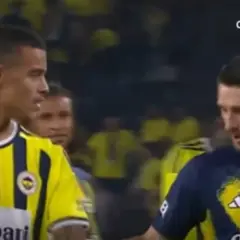 Piłkarze w żółto-granatowych strojach, jeden z nich to Mason Greenwood, rozmawiają na boisku.