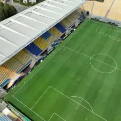 Puste trybuny stadionu Ennio Tardini, z zieloną murawą i białymi liniami boiska.