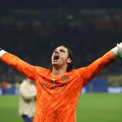 Bramkarz Yann Sommer w pomarańczowej koszulce z podniesionymi rękami świętuje zwycięstwo.