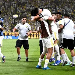 Piłkarze świętują zwycięstwo, przytulając się na boisku. W tle tłum kibiców, którzy przyszli zobaczyć, kiedy gra Ronaldo.