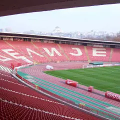Puste trybuny stadionu Crvena Zvezda czekają na kibiców. Na tle miasta widać charakterystyczną kopułę.