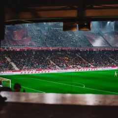 Piłkarz na boisku podczas meczu Wolfsberger – RB Salzburg. Trybuny pełne kibiców, wielkie banery na stadionie.
