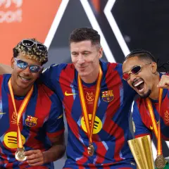 Trzej zawodnicy FC Barcelony w okularach przeciwsłonecznych świętują zdobycie Superpucharu Hiszpanii.