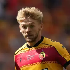 Kamil Jóźwiak w żółto-czerwonej koszulce piłkarskiej, z charakterystyczną fryzurą i skupionym spojrzeniem.