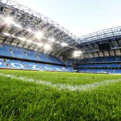Zielona murawa i niebieskie trybuny stadionu Lecha Poznań, gotowe na kolejny mecz.