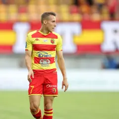 Piłkarz Dominik Marczuk w żółto-czerwonej koszulce z numerem 7 i czerwonych spodenkach na boisku.