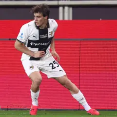Piłkarz Parma Calcio 1913 z numerem 25 na koszulce w białym stroju z czarnymi elementami, gotowy do akcji na boisku.
