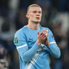 Erling Haaland w błękitnej koszulce Manchesteru City, z pucharem Carabao Cup na rękawie, klaszcze na boisku.