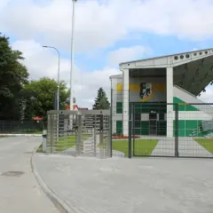 Nowoczesny stadion w Białej Podlaskiej z trybunami, bramami i obrotowymi kołowrotkami.