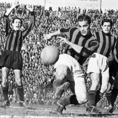 A.C. Milan – zawodnicy w akcji. Piłkarze w pasiatych koszulkach walczą o piłkę na tle trybun pełnych kibiców.