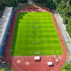Piłkarze trenują na zielonej murawie stadionu Floty Świnoujście, otoczonego drzewami.