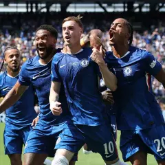 Radość zawodników Chelsea F.C. po zdobytej bramce. Piłkarze w niebieskich strojach świętują razem na boisku, otoczeni przez kibiców.