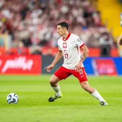 Bartosz Slisz w białej koszulce z orłem na piersi, w akcji na boisku.