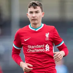 Młody piłkarz Mateusz Musiałowski w czerwonej koszulce Liverpoolu, z dumą nosi herb klubu.