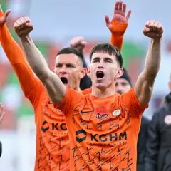 Marcel Reguła świętuje z drużyną, wznosząc ręce w geście radości.