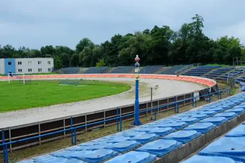 Puste trybuny stadionu Wandy Kraków z widokiem na tor żużlowy i boisko.