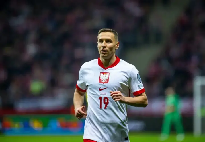 Piłkarz Przemysław Frankowski w białej koszulce z numerem 19, reprezentujący Polskę. Jego obecne drużyny to RC Lens i reprezentacja Polski.