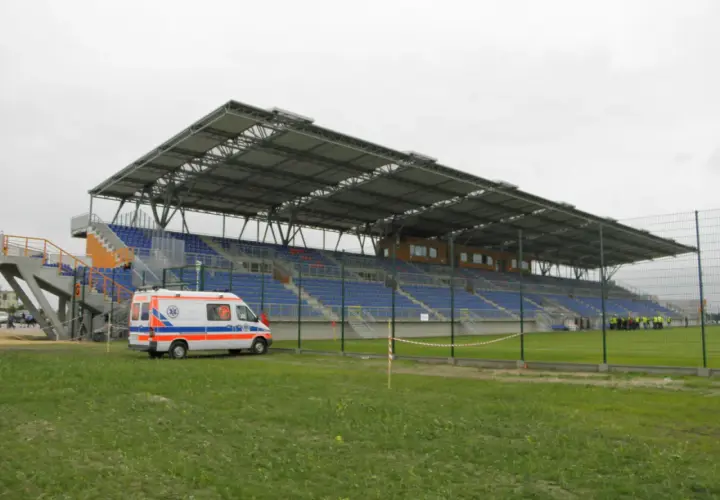Pogoń Siedlce stadion z ambulansem na murawie. Puste trybuny czekają na kibiców.