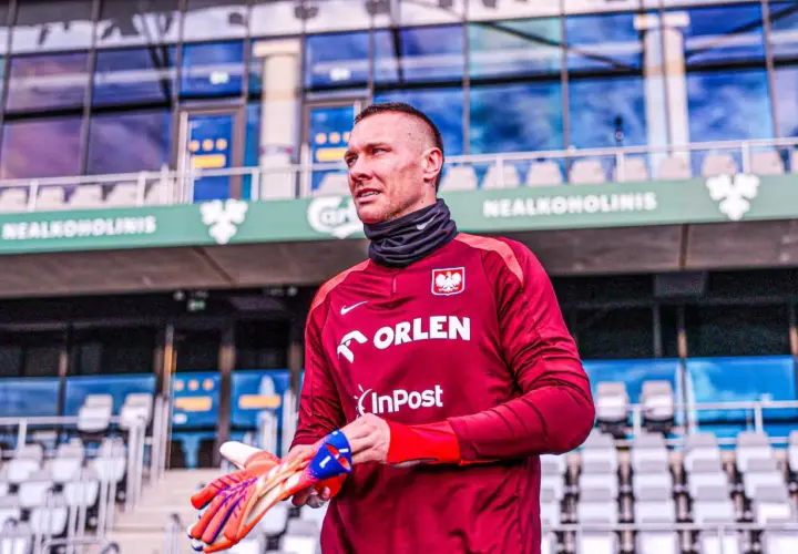 Bramkarz w bordowej koszulce z orłem, gotowy do gry. Gdzie gra Skorupski? Na stadionie, wśród pustych trybun.