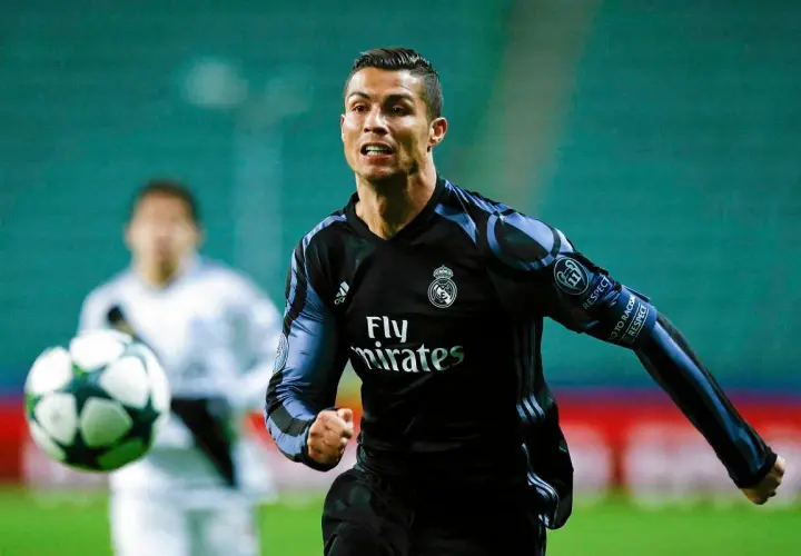 Cristiano Ronaldo w czarnej koszulce Realu Madryt biegnie z piłką.