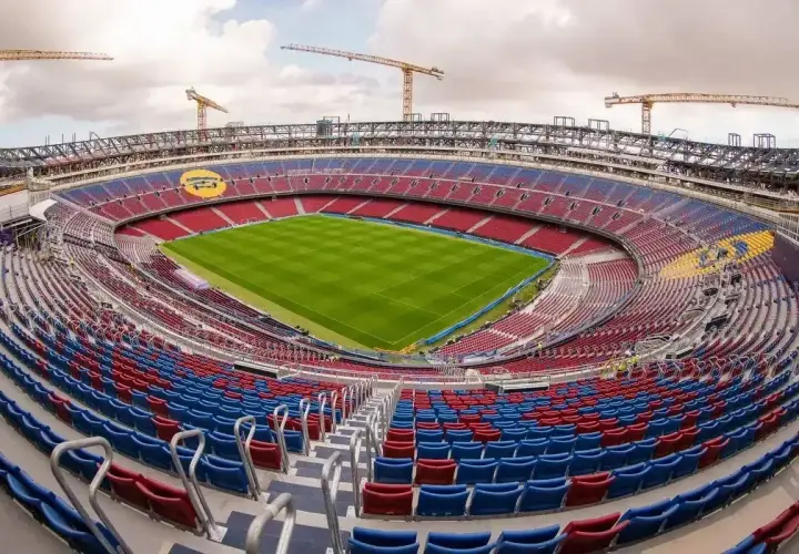 Widok na Camp Nou, największy stadion w Hiszpanii, w trakcie modernizacji. Żurawie budowlane górują nad trybunami w barwach czerwono-niebieskich.