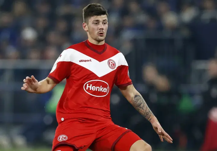 Jeden z zawodników Hertha BSC w czerwonej koszulce z białymi elementami i logo "Henkel" na piersi, z tatuażem kompasu na ramieniu.