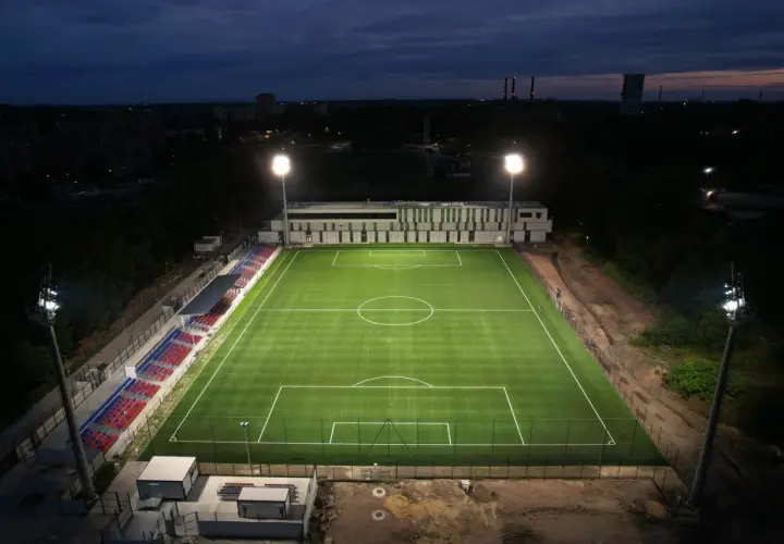 Piękny, oświetlony stadion Polonii Bytom nocą. Zielona murawa i czerwono-niebieskie trybuny czekają na kibiców.